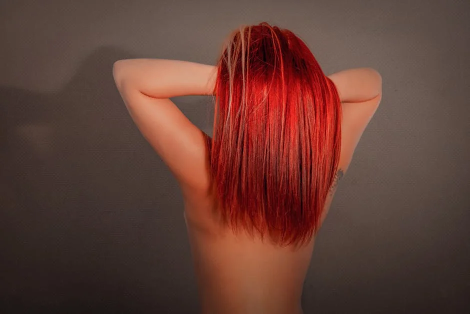Striking studio portrait of a woman showcasing vibrant red hair, posing indoors.